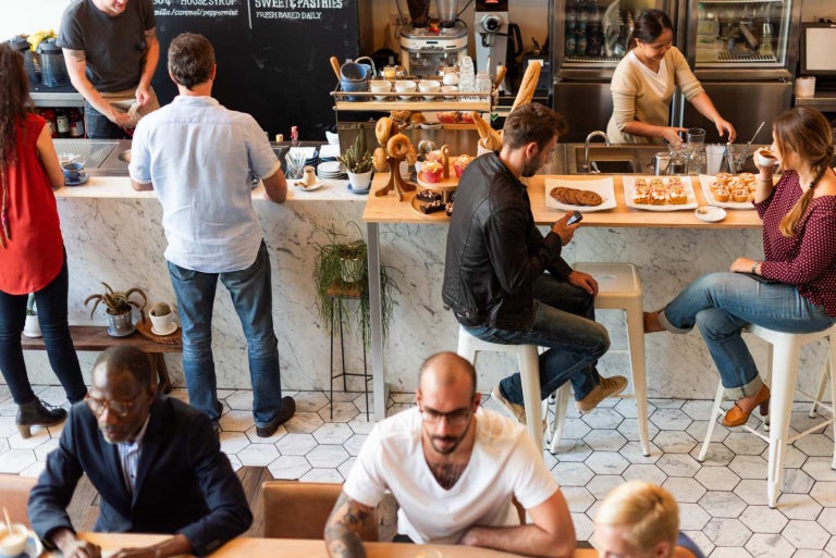 A busy cafe with diverse people enjoying coffee and pastries