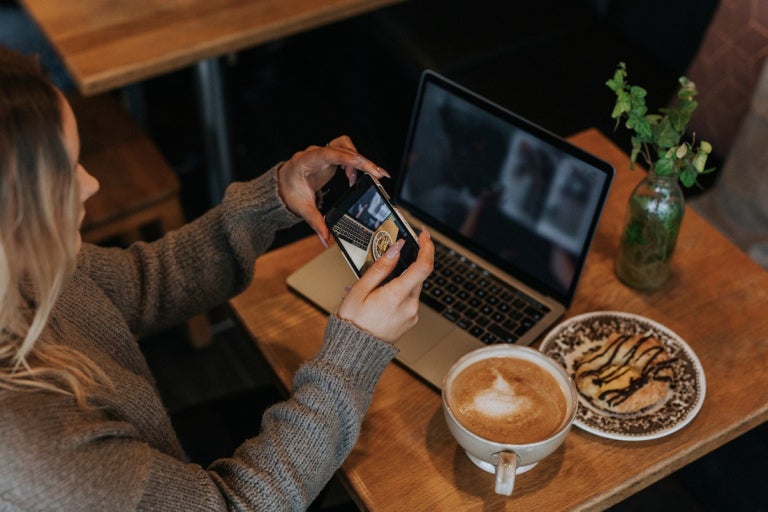 Woman working in a coffee shop taking a photo of her order
